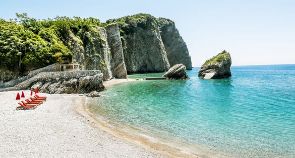 Photo of the beach and the cliffs on the island of St. Nicholas in Budva, Montenegro.