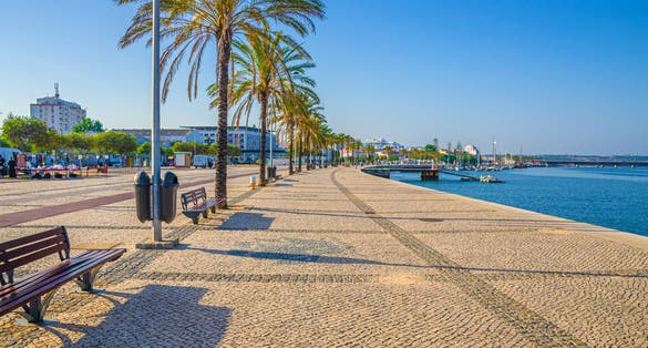 Photo of Ribeirinha de Portimao town, cobblestone embankment promenade of Arade River in city centre.