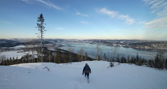 Lonely man walking down on background of Drammen fjord in winter time, Norway.