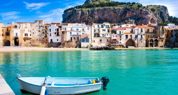 Photo of fishing boat in Cefalu, medieval town on Sicily island, Italy. Seashore village with beach and clear turquoise water of Tyrrhenian sea.