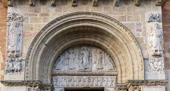 View of the ancient romanesque tympanum representing the Ascension of Christ with angels and the apostles at St Sernin basilica, Toulouse, France