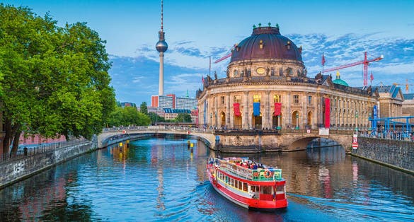 Beautiful view of UNESCO World Heritage Site Museumsinsel (Museum Island) with excursion boat on Spree river and famous TV tower in the background in beautiful evening light at sunset, Berlin.