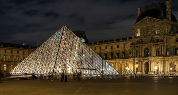 Photo of the Louvre glass pyramid illuminated at night, Paris, France.
