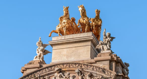 Photo of sculptures of angels and a golden horses from Aurora Quadriga on the top of the Font de la Cascade in Barcelona, Spain.