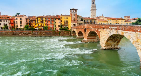 photo of Ancient Roman bridge Ponte Pietra and the River Adige in cloudy summer day, Duomo tower in background, Verona, Italy .