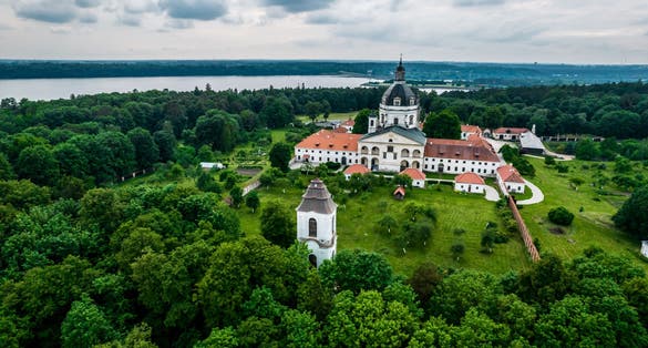 photo of aerial view of pazaislis monastery and surrounding lush geen landscape during summer evening.