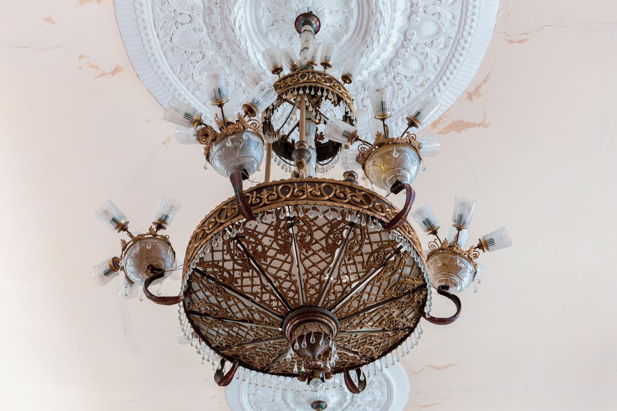 Old style vintage brass crystal chandelier in Niko Berdzenishvili Kutaisi State History Museum, main exhibition room, gypsum ornaments on the ceiling.