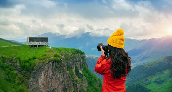 Photo of tourist take a photo near Russia Georgia friendship monument on the georgian military road at the Jvari pass, Georgia.