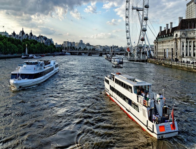 Thames River cruise boats sailing past the London Eye during golden hour..jpg