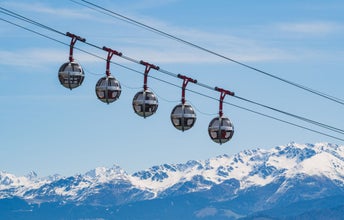 Gondola bubbles against the blue sky and the French Alps in the background. Cable car taking tourists to Fort de La Bastille in Grenoble, France