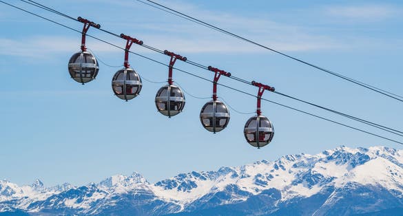 Gondola bubbles against the blue sky and the French Alps in the background. Cable car taking tourists to Fort de La Bastille in Grenoble, France