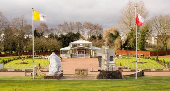 Photo of Look at the Park in Grotto, in Carfin, Scotland. Photo Showing Vatican Flag on Left, Polish Flag at Right and Glass Chapel at the Back.