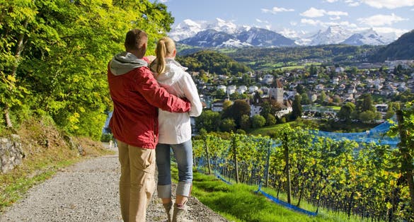 photo of travelers on the top of a hill looking at Spiez Castle in Spiez, Switzerland.