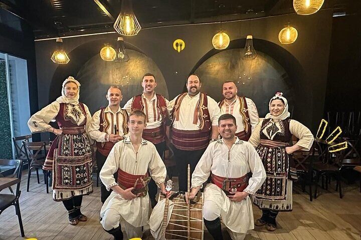 A group of people in traditional Balkan clothing pose with a drum inside a cozy restaurant in Skopje..jpg