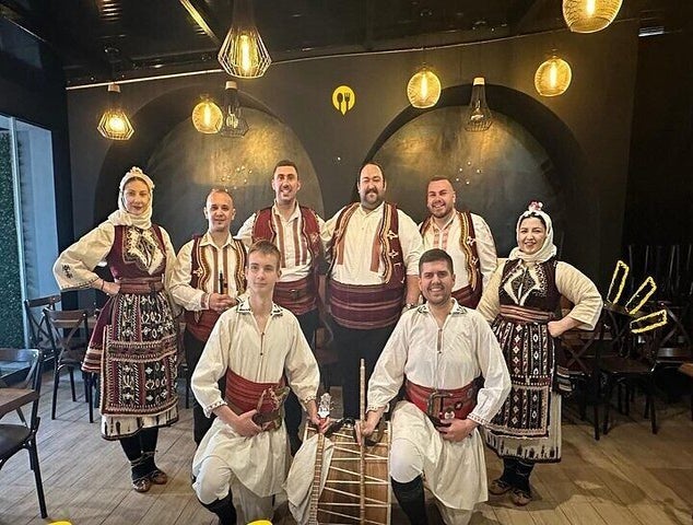 A group of people in traditional Balkan clothing pose with a drum inside a cozy restaurant in Skopje..jpg