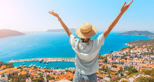 Happy woman with open arms stands on the viewpoint and enjoys the panorama of Kas.