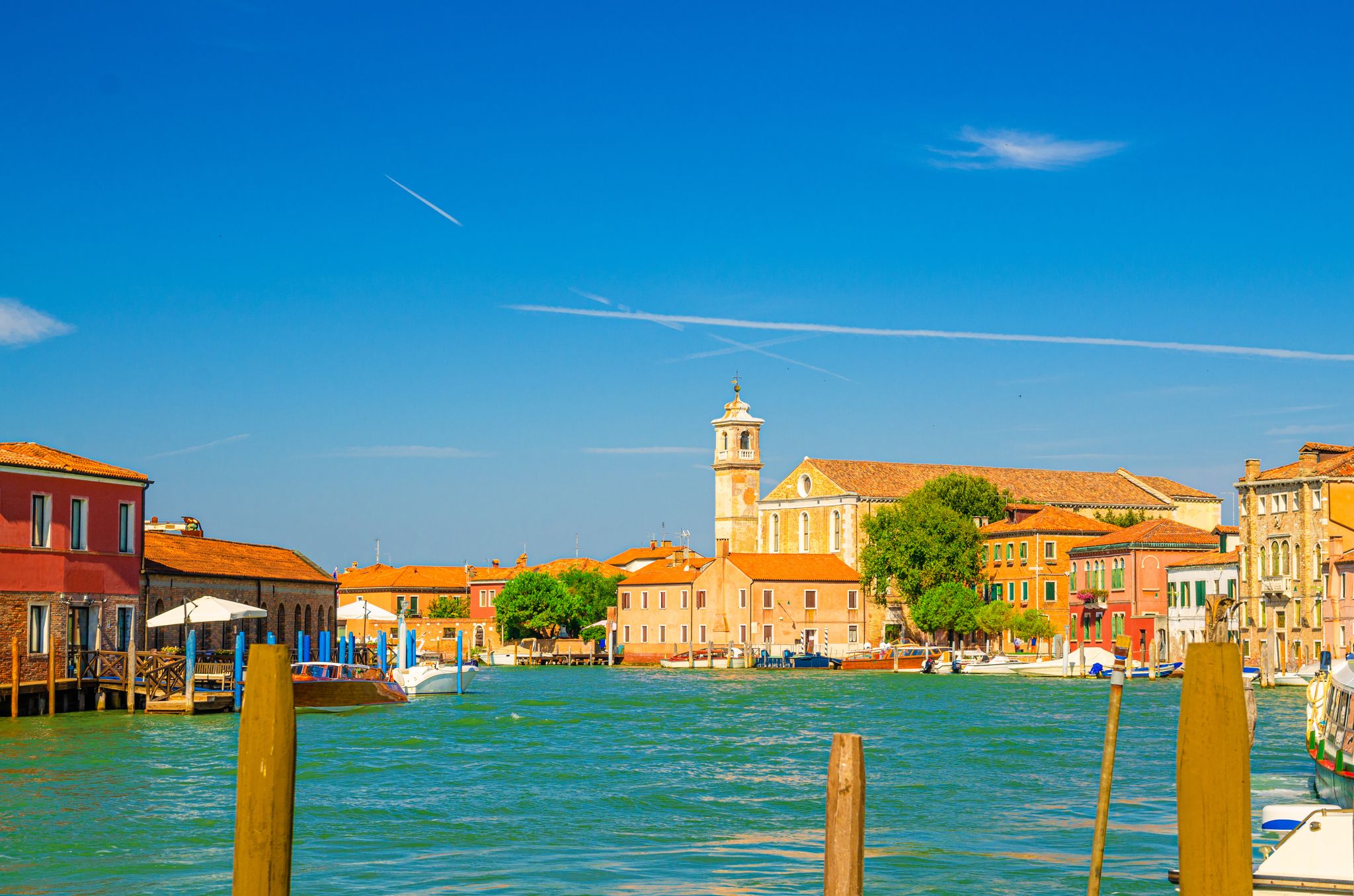 Photo of Murano islands water canal with Santa Maria degli Angeli church in Italy.