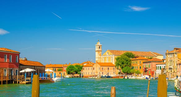 Photo of Murano islands water canal with Santa Maria degli Angeli church in Italy.