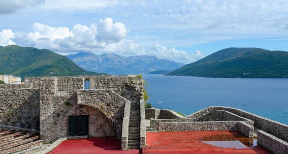 Photo of Fortress Kanli-Kula (Bloody Tower) against backdrop of Bay of Kotor and mountains, Herceg Novi, Montenegro.