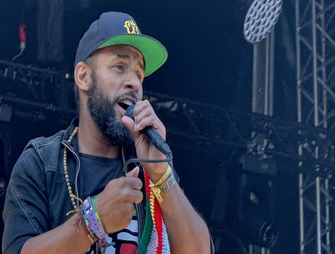 Mitchell Brunings performing on stage with a microphone and Surinamese flag scarf..jpeg