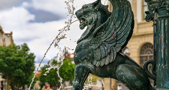 Photo of 19th century Roman-style marble Fountain of the Lions or Fonte dos Leoes featuring 4 winged lions on Praca de Gomes Teixeira square in Porto, Portugal.