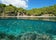 photo of Mediterranean Sea coastline with tourists in summer and a school of fish underwater, split view above and below water surface in Cala Rostella, Roses, Girona, Spain.