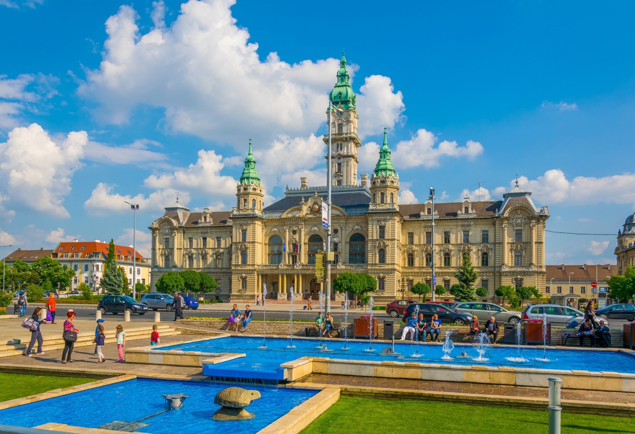 People are sitting around a singing fountain situated in front of the town hall in the hungarian city Gyor.