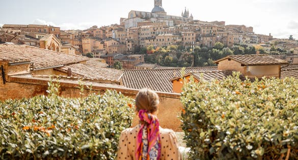 photo of view of Stylish woman walks on background of cityscape of Siena old town. Concept of travel famous cities in Tosacny region of Italy