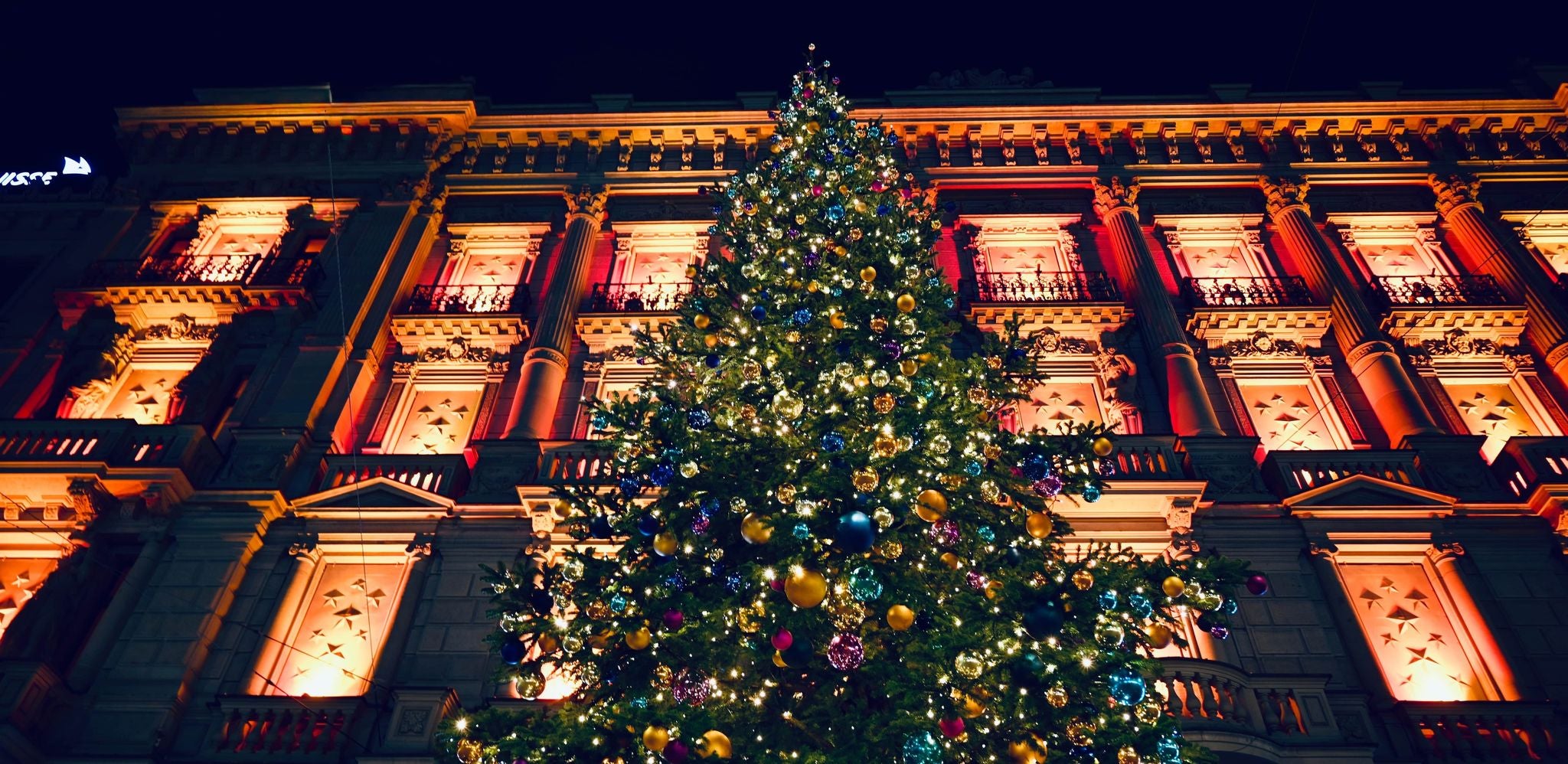 Giant Christmas tree lit up in front of a grand building during December in Switzerland..jpg