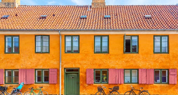 Photo of old yellow house of Nyboder district with bikes. Old Medieval district in Copenhagen, Denmark.