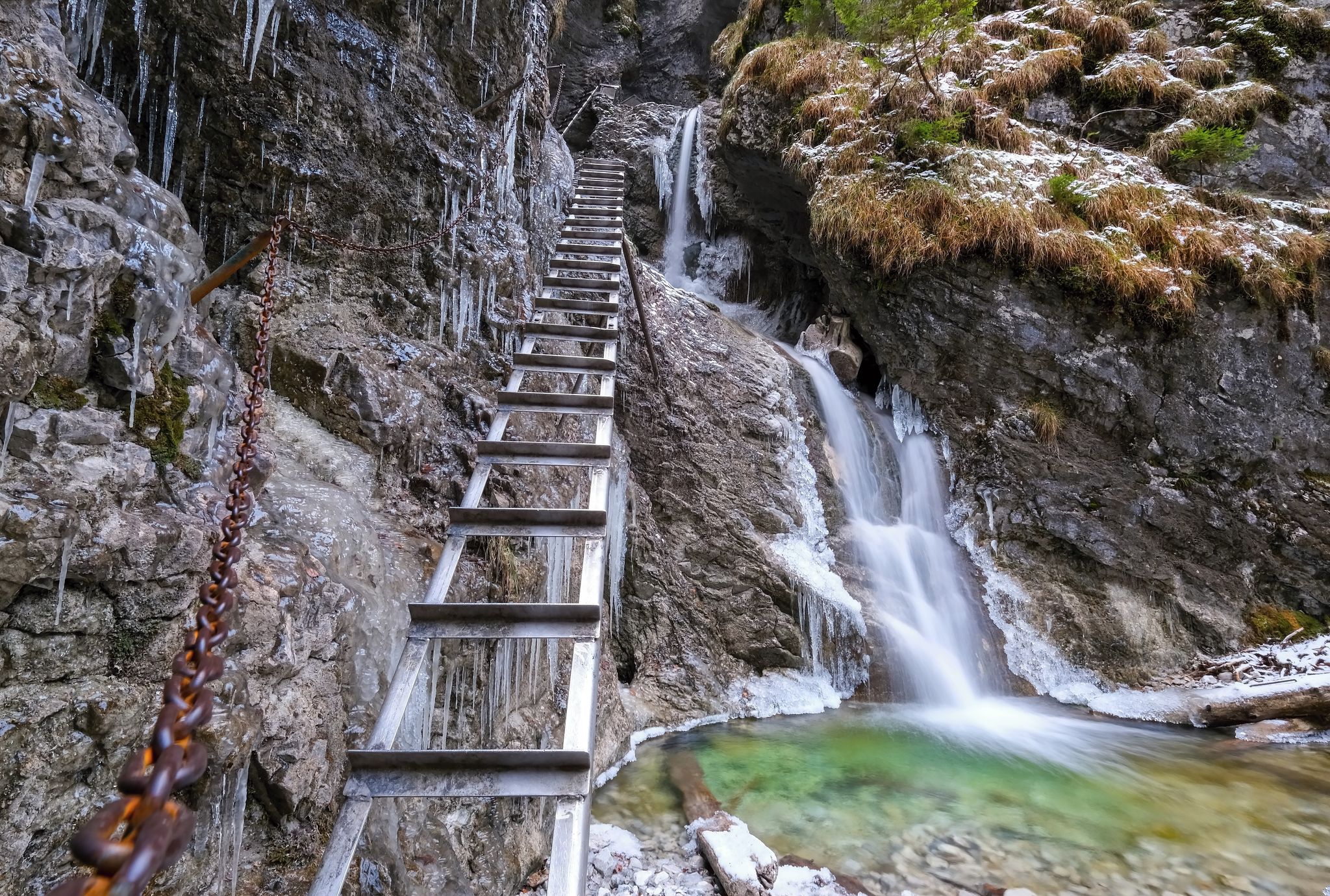 Waterfall with ladder in canyon, sucha bela.Icefall in the gorge of Slovak paradise national park. Winter hiking trail with ice structures and steel climbing ladder. Adventure travel in Slovakia
