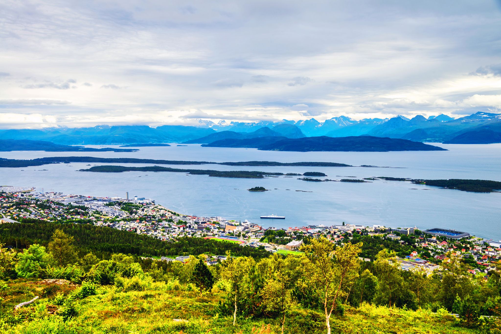 photo of view of Molde, Norway. Aerial day view of Molde, Norway during the cloudy afternoon. Beautiful fjord with snowy mountains in summer