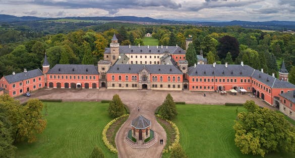 Photo of aerial view of Sychrov Castle with typical pink facade. Neo-Gothic style chateau with beautiful english style park, Czech Republic.