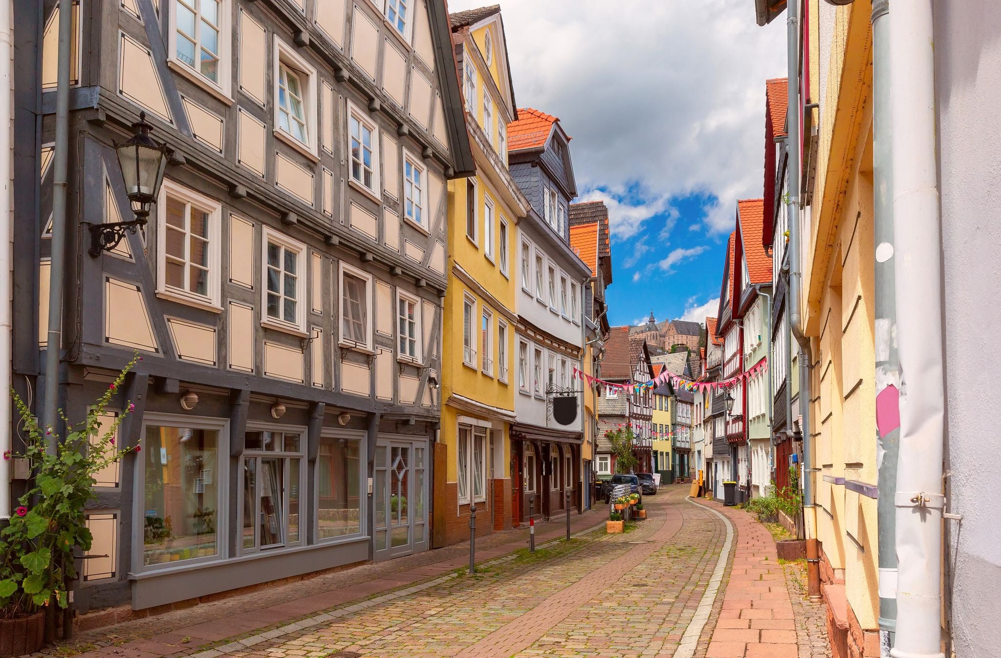 Photo of traditional timber-framed houses line the cobblestone street leading to Marburg Castle, Germany.