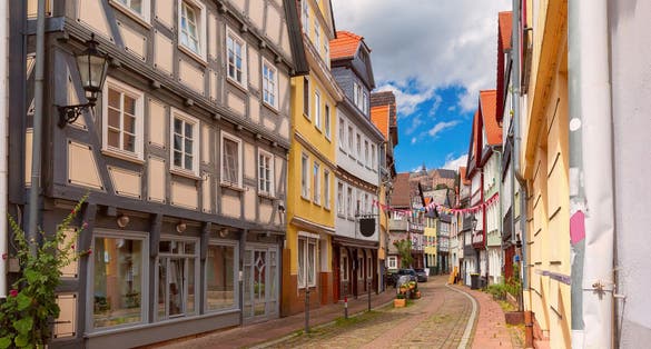 Photo of traditional timber-framed houses line the cobblestone street leading to Marburg Castle, Germany.