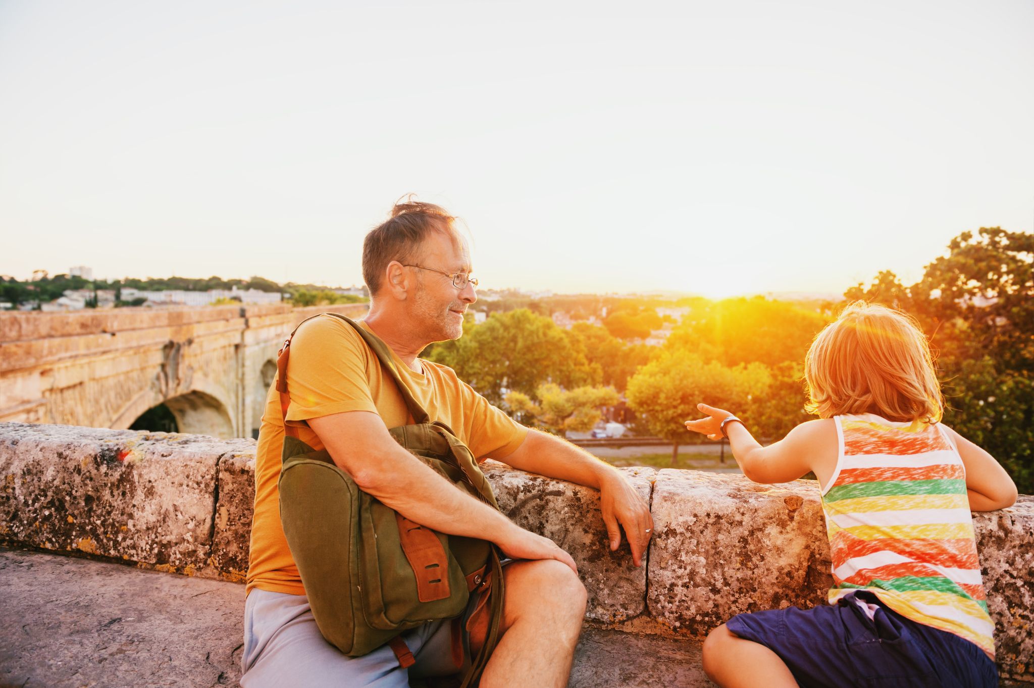 photo of happy tourists, father and son enjoying sunset at Saint Clement Aqueduct in Montpellier, France.