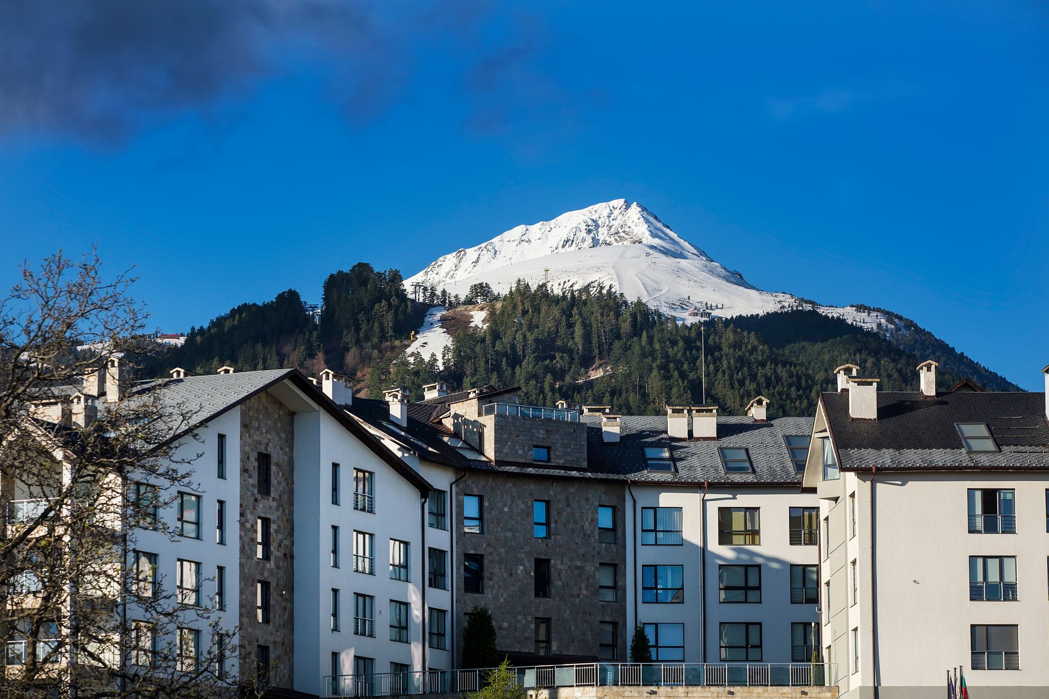 Photo of A hotel with the Bansko Ski Resort on the Pirin Mountains at the background in Bansko, Bulgaria.