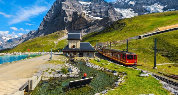 Photo of Cogwheel red passenger train in the small mountain station. Small train station on the shore of the Fallbodensee lake, Jungfraujoch, Bernese Oberland, Switzerland.