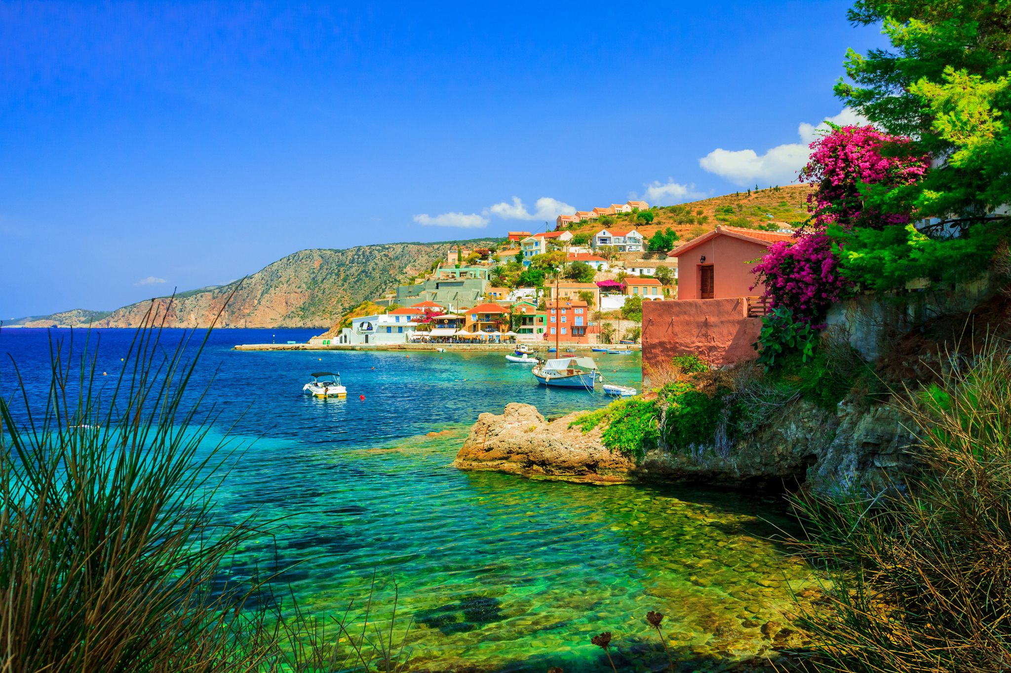 Photo of white boat in crystal clear blue sea water, Argostoli, Greece.