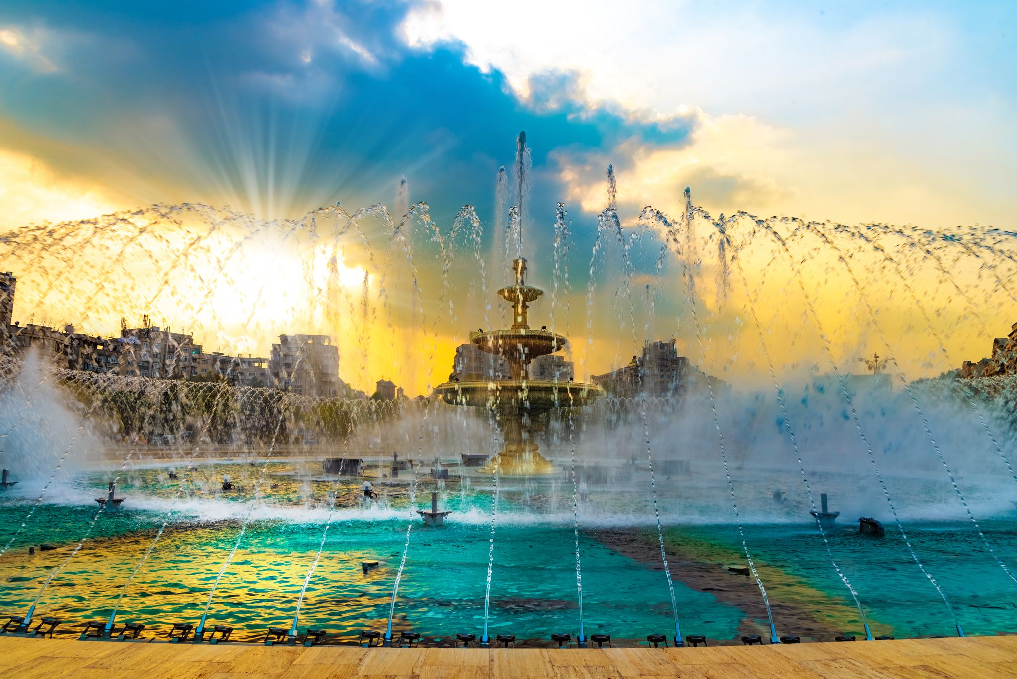 Beautiful background with the famous fountain against colorful sky in central square of Bucharest, in sunset light.