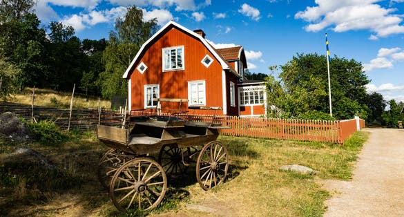photo of old carriage in front of red wooden farming house on Katthult farmyard in Gibberyd, Sweden.