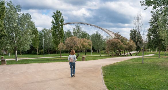 Photo of Woman with her back walking along the paths of the park next to the Ebro River in the city of Zaragoza, Spain.