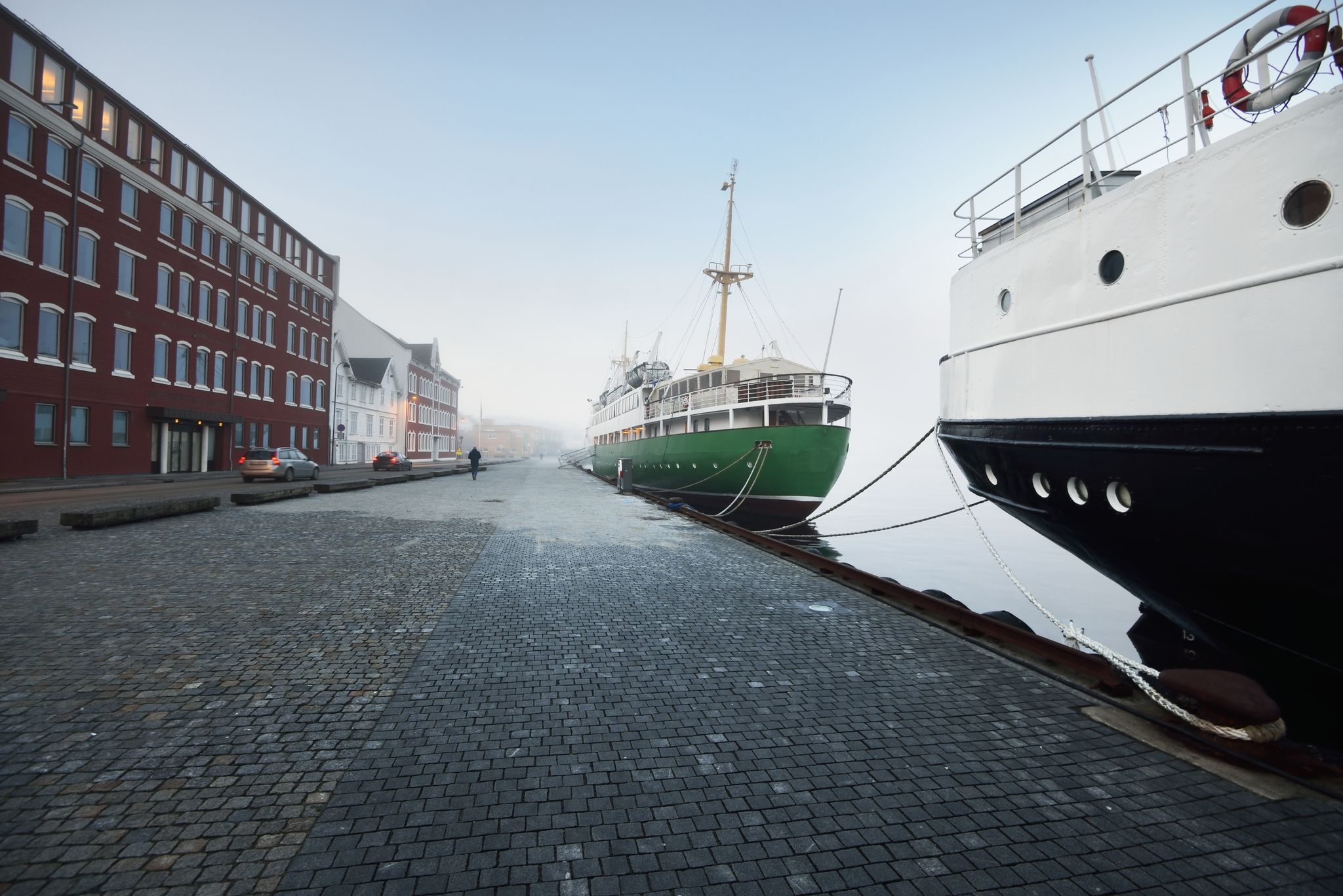 Green training ship moored to a pier in a city center. Stavanger embankment, Norway. Travel destinations, sightseeing, landmark, tourism, cruise, regatta, expedition, research, work, traditional craft