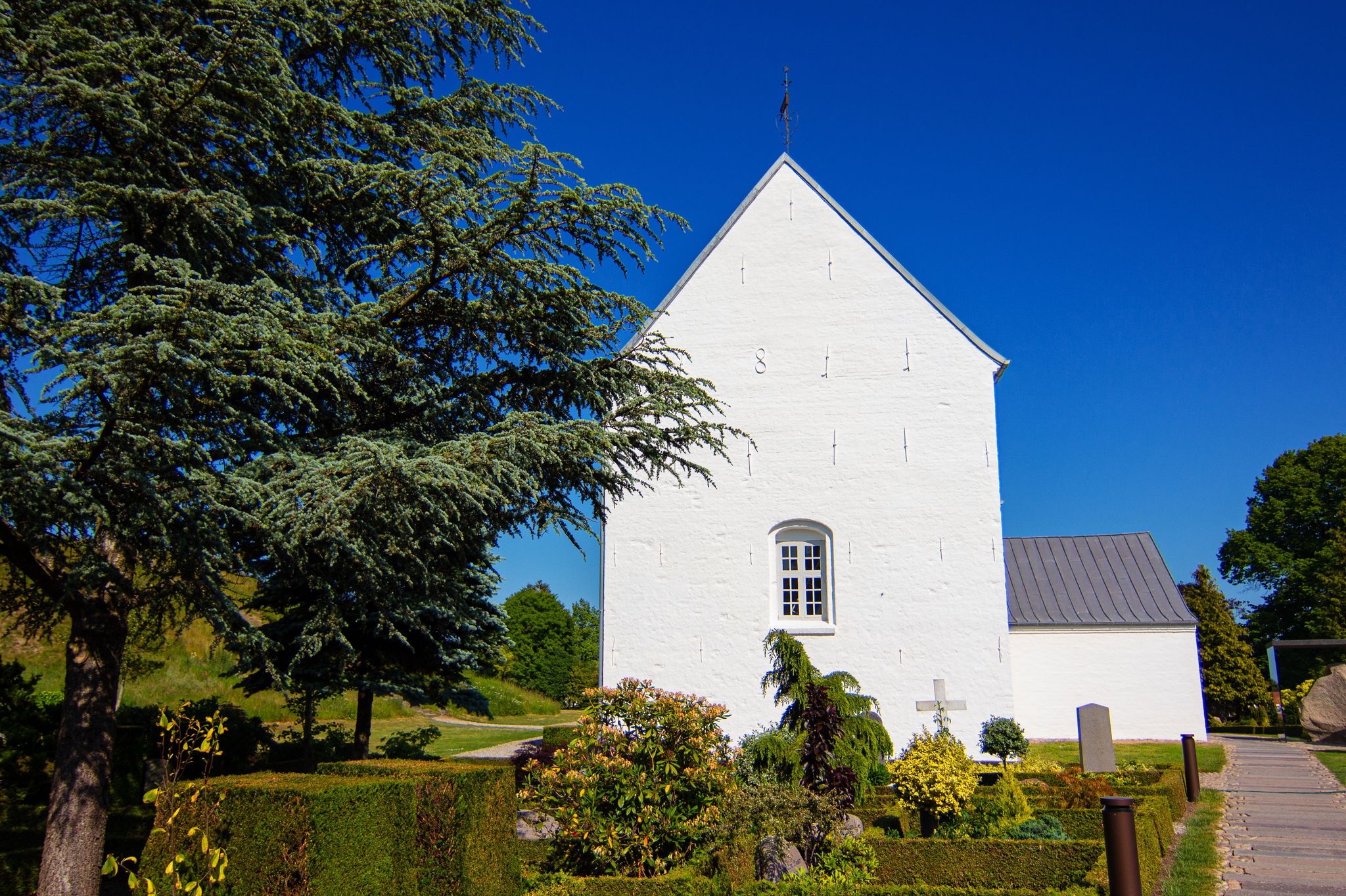 Photo of Jelling Church and small local cemetery in Jelling village at, Jutland, Denmark. It was built of limestone around the year 1100.