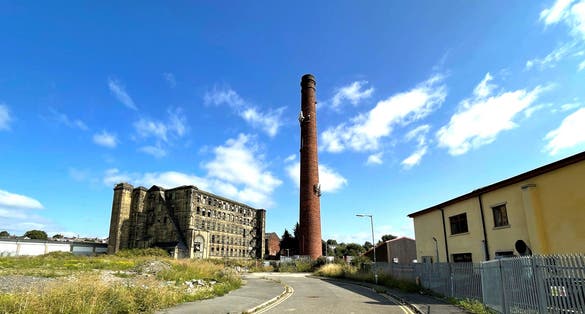 Tall Victorian red brick chimney, next to an old derelict mill, in the post industrial city of, Bradford, Yorkshire, UK