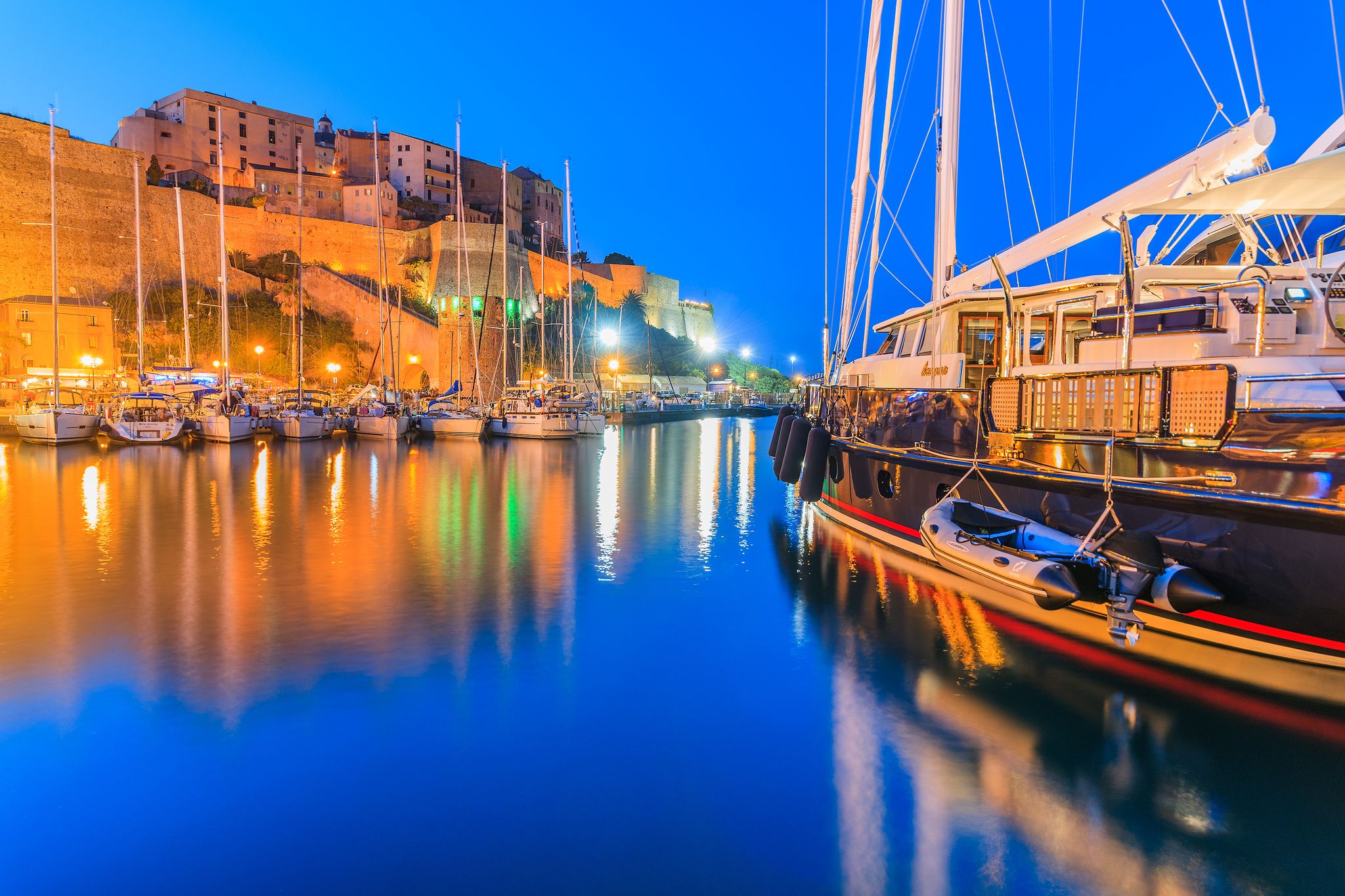 Photo of aerial view from the walls of the citadel of Calvi on the old town with historic buildings and bay with yachts and boats, Corsica, France.