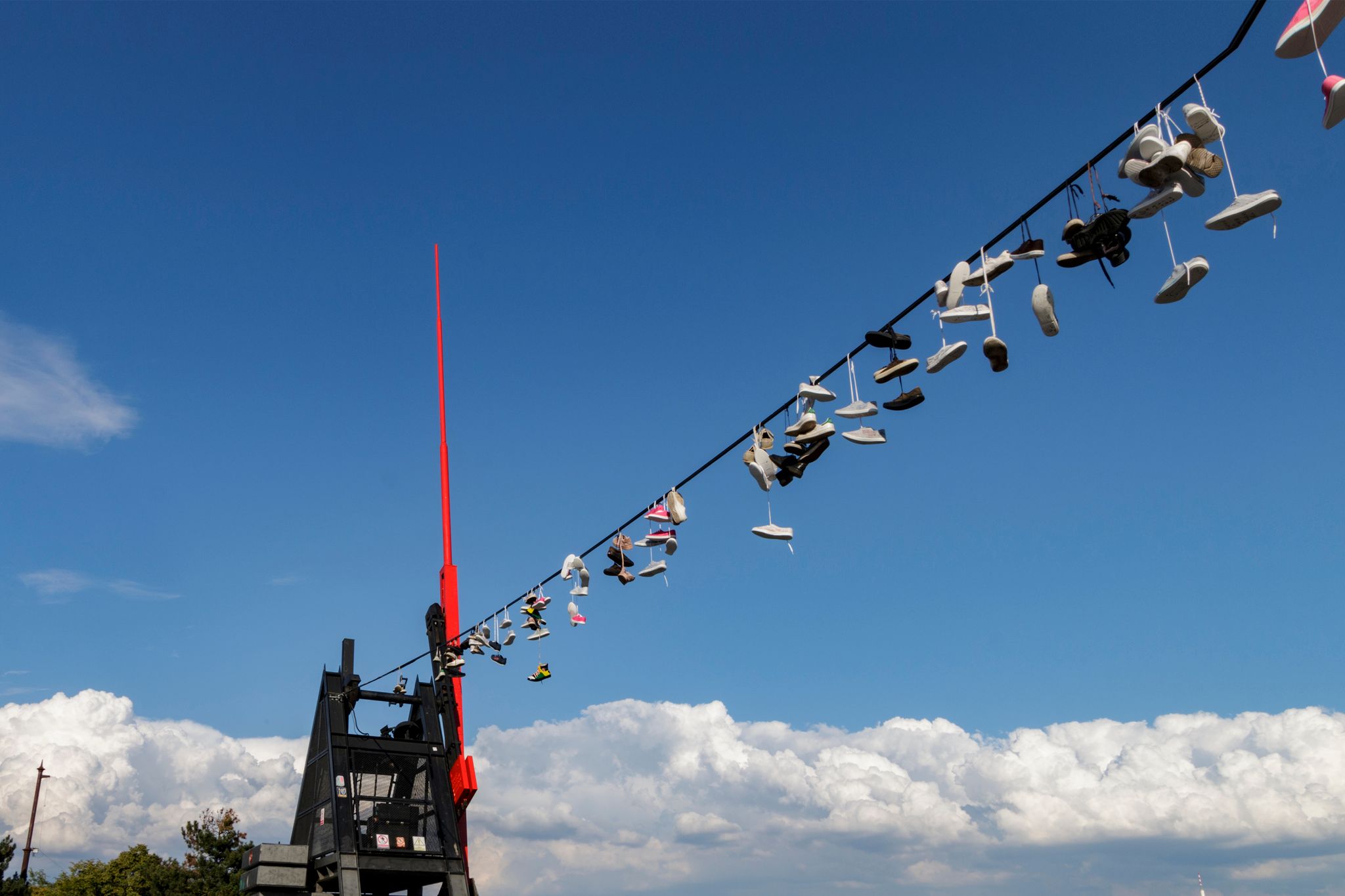 Photo of hanging sneakers on the wire of the Prague Metronome a giant, functional metronome in Letna Park, overlooking the Vltava River and the city center of Prague, Czechia.