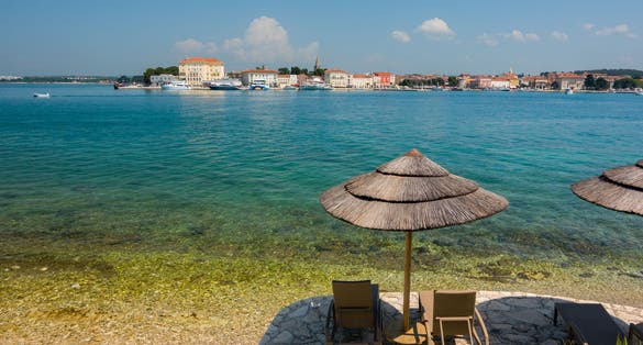 Photo of Beach and resort with beach chairs and umbrellas in morning light on the beach of a Croatian seaside holiday resort in Porec.