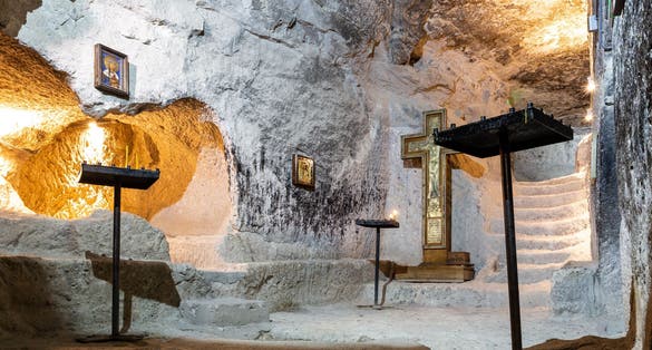 Photo of Remains of the Old Church carved in the rock in Vardzia Cave Monastery complex in Georgia with stone walls, orthodox icons and cross.