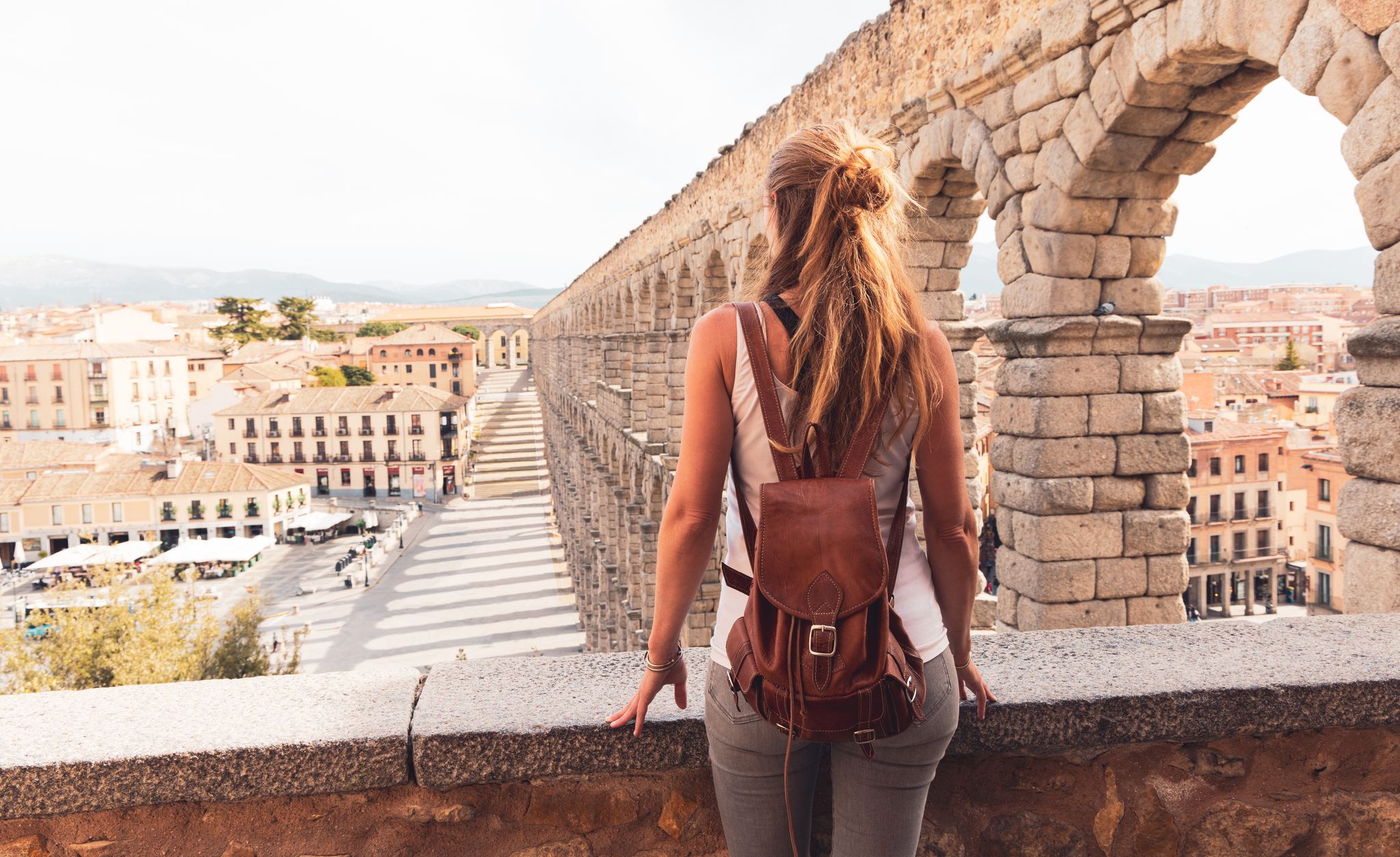 Photo of woman tourist enjoying view of Roman aqueduct on plaza del Azoguejo in Spain.